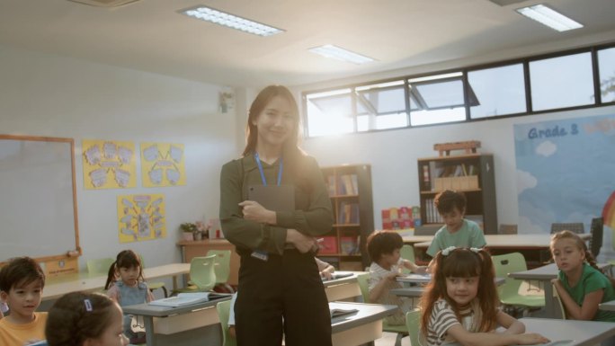图为站在教室里对着镜头微笑的亚洲小学老师。