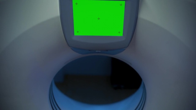 镜头从绿屏平移到病人:医学实验室或医疗机构使用高科技设备对躺在CT或MRI上的女性进行扫描，同时机器