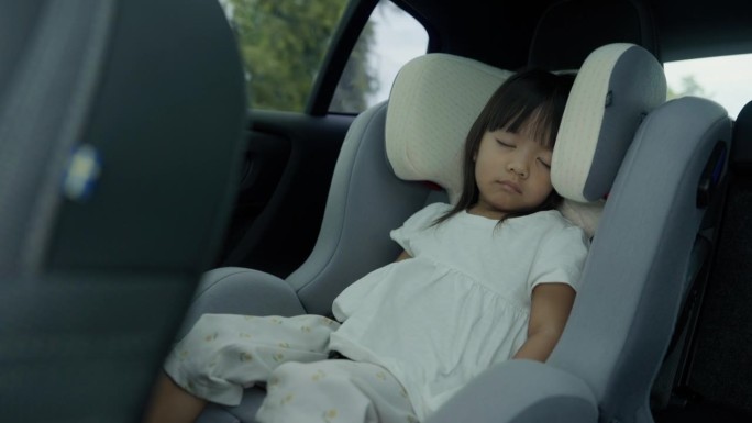 可爱的亚洲小女孩和家人一起旅行时坐在汽车座椅上睡觉。