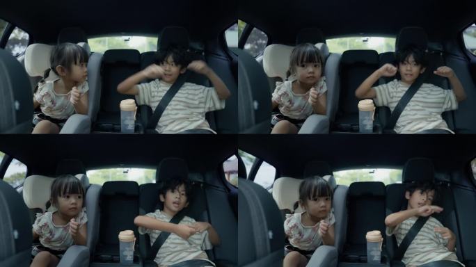 快乐的小男孩和妹妹在旅行时坐在汽车后座唱歌
