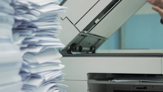 办公室的桌面上有一堆文件等着用复印机复印。