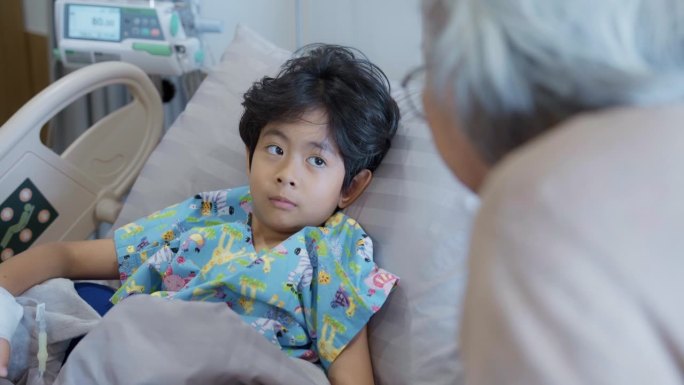放松的年轻亚洲病人躺在医院的床上和奶奶聊天