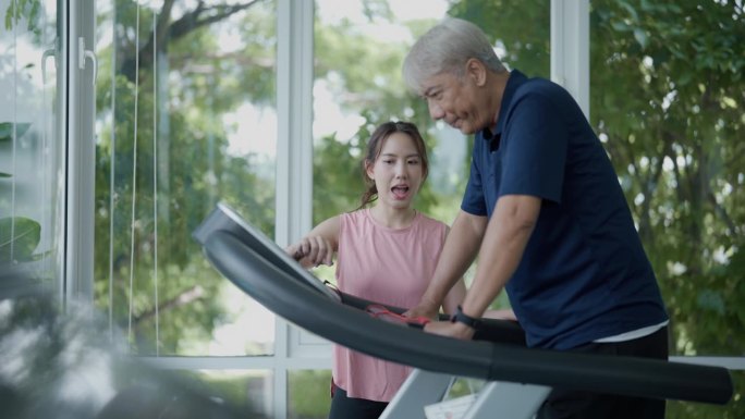老人在健身俱乐部和教练一起制定健身计划。在跑步机上锻炼的老人在健身房康复期间与他的教练交谈。