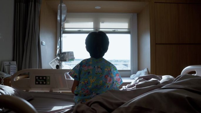 一个患感冒的孩子的后视图，他很无聊，在医院过周末。望着窗外