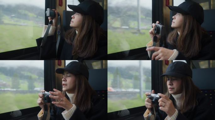 一名心情愉快的女子乘火车去瑞士山区度假时，从车窗拿起相机拍摄。
