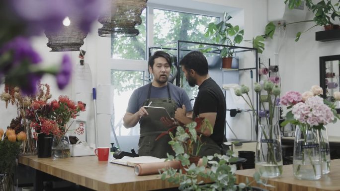 两名男性花店老板在数码平板电脑上清点库存