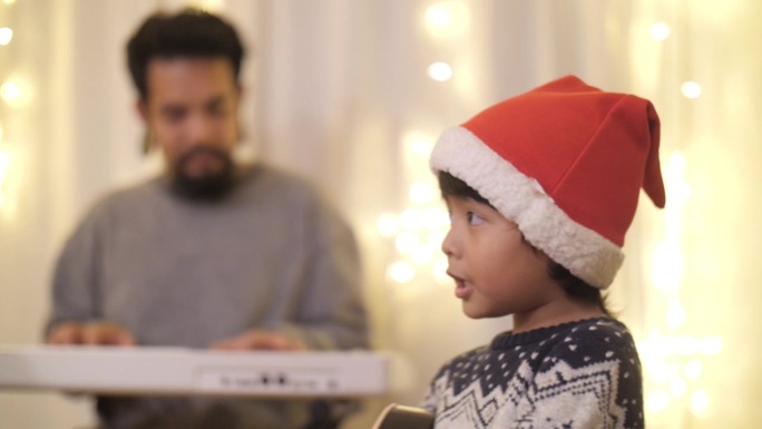 可爱的亚洲儿子和善良的父亲在客厅享受音乐与圣诞主题的家庭。