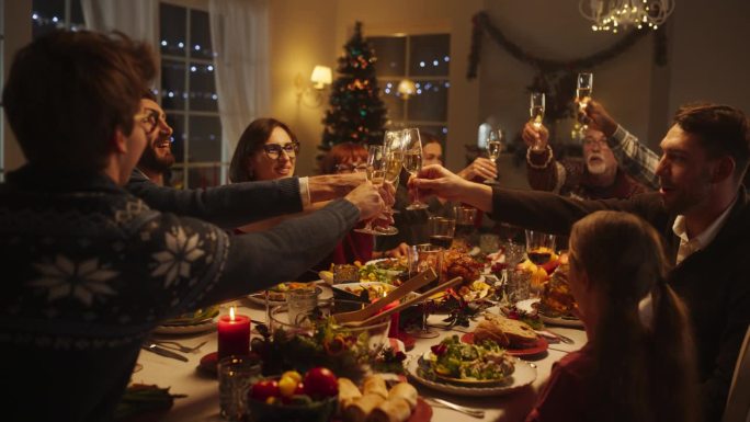 在家里与多元文化的亲人一起庆祝圣诞夜，享受火鸡晚餐。老人和年轻的家庭成员举杯碰杯庆祝节日