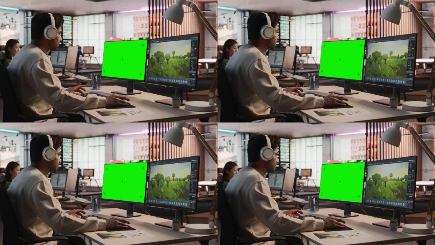 印度男性游戏设计师使用带有绿屏Chromakey的桌面电脑，在3D建模软件中为新视频游戏设计沉浸式世