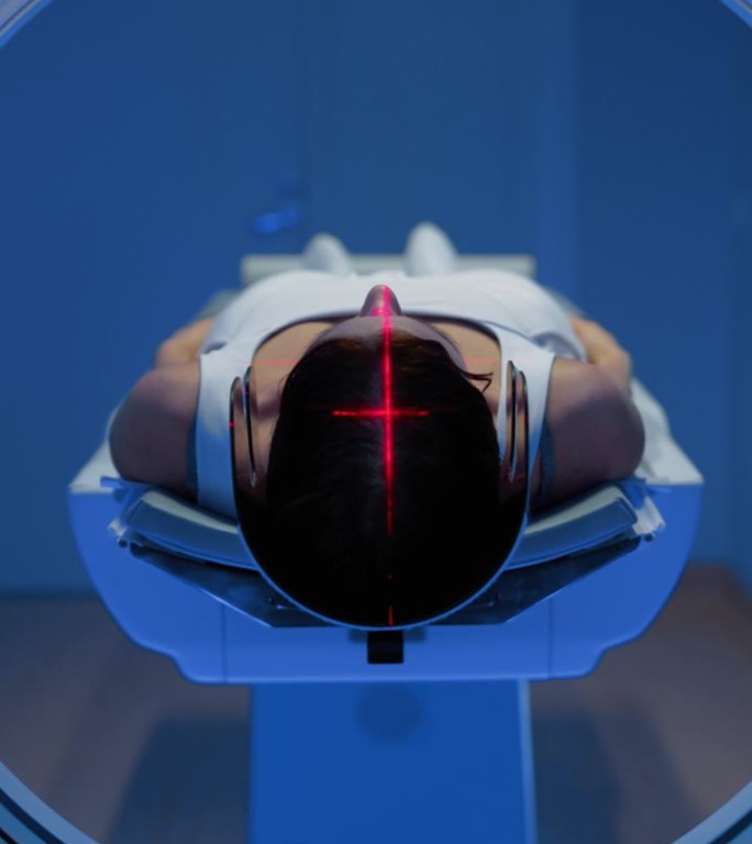 垂直屏幕:在医学实验室，躺在CT或MRI扫描床上的匿名女性患者的镜头正在接受红色激光的扫描程序。床向