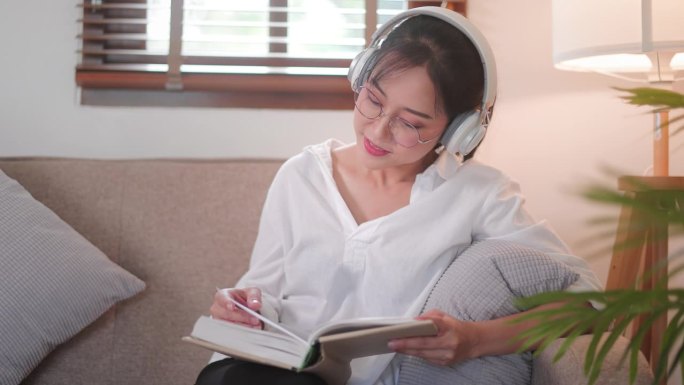 美丽的亚洲女人在客厅看书和大笑。
