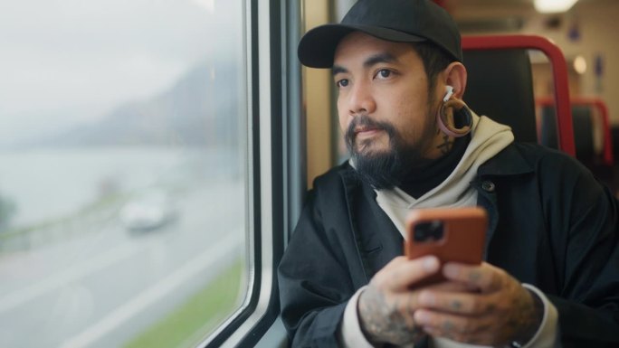 亚洲游客在乘坐火车时用手机阅读和聊天。