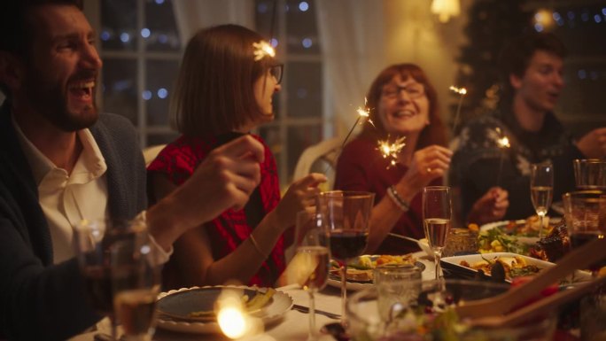 与父母，孩子和朋友在一个舒适的家一起享受圣诞晚餐的肖像。亲戚们一起吃饭，一起唱传统节日歌曲，一起点烟