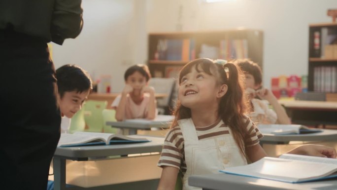 一个年轻的亚洲女孩在教室里专心地回答幼儿园老师的问题。