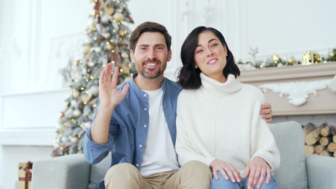 摄像头的观点。在冬季，新年，圣诞节，幸福的家庭夫妇坐在家里房间的沙发上进行视频通话