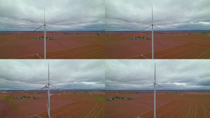 在广阔的天空下，爱荷华州广阔的农田里，风力涡轮机占据了前景。