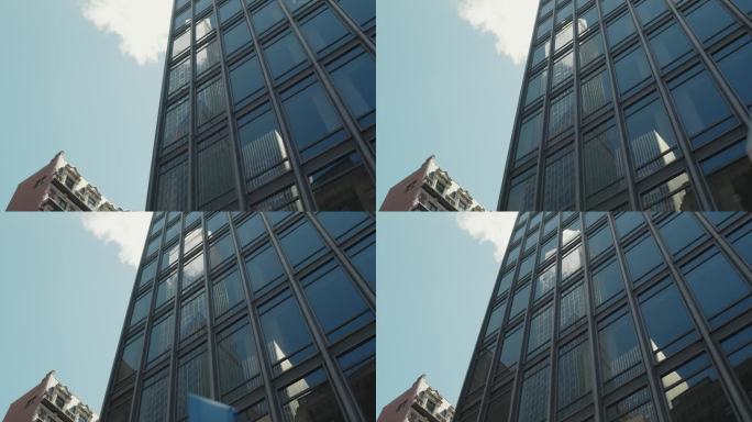 从现代玻璃建筑反射的商业摩天大楼的低角度镜头。在一个晴朗的晴天，从一辆移动的汽车上拍摄的纽约城市建筑