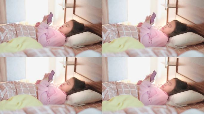 可爱的亚洲女孩在睡觉前用智能手机躺在床上