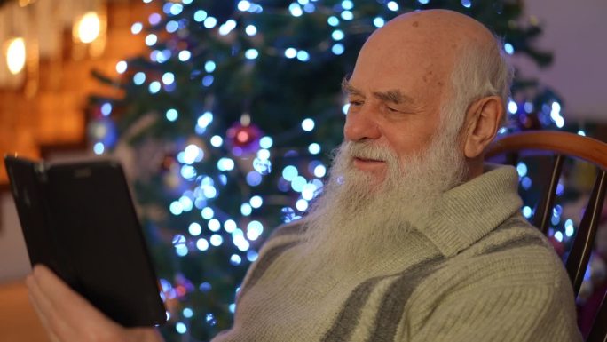 一位老人在一棵闪闪发光的圣诞树前进行视频通话。