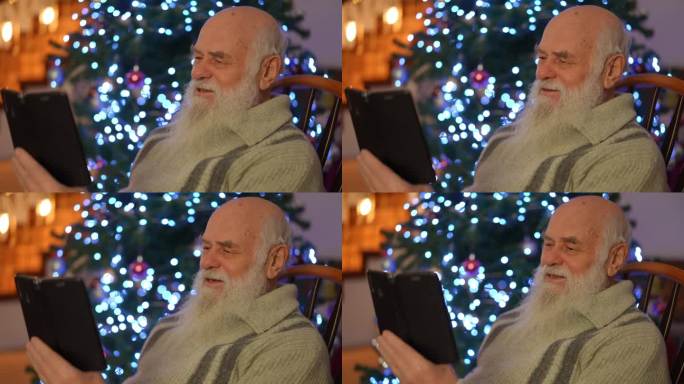 一位老人在一棵闪闪发光的圣诞树前进行视频通话。