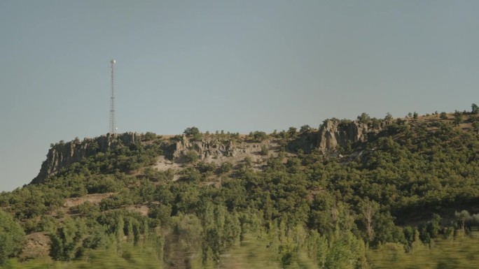 从一辆路过的汽车上看到一座高山，山顶上有一个手机信号塔。