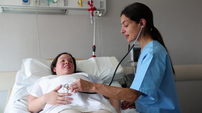 开朗的产科医生用听诊器检查一位紧张的等待分娩的母亲