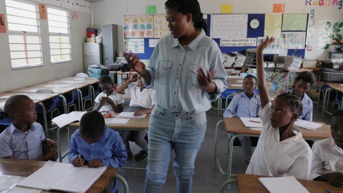 特写镜头。非洲黑人女教师在教室里一边走路一边教非洲孩子