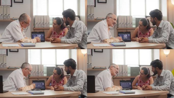 印度夫妇在医院预约医生的画像。专业神经科医生使用核磁共振扫描图像和数字平板电脑给病人诊断和建议