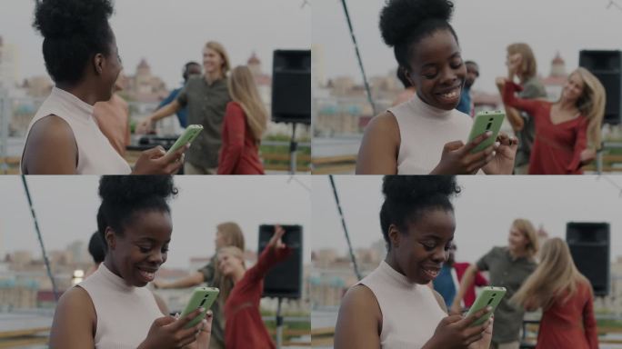 在屋顶的露天派对上，快乐的女人用智能手机发短信，微笑着享受在线交流