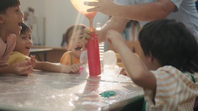 孩子们对小苏打和醋的化学反应产生二氧化碳感到兴奋。然后开始吹气球