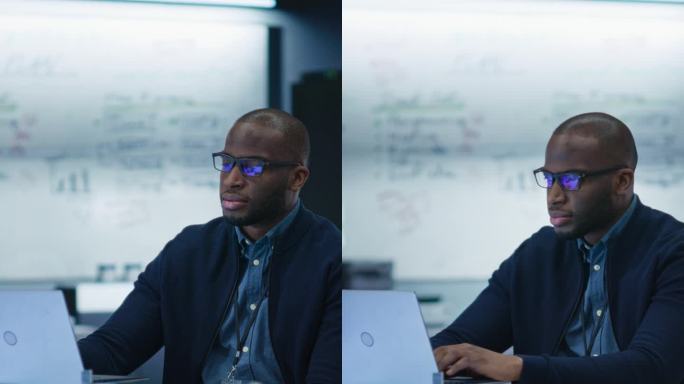竖屏:现代办公用笔记本电脑改进电路板的男性专家肖像。人工智能项目的黑人工程师思维和打字思路