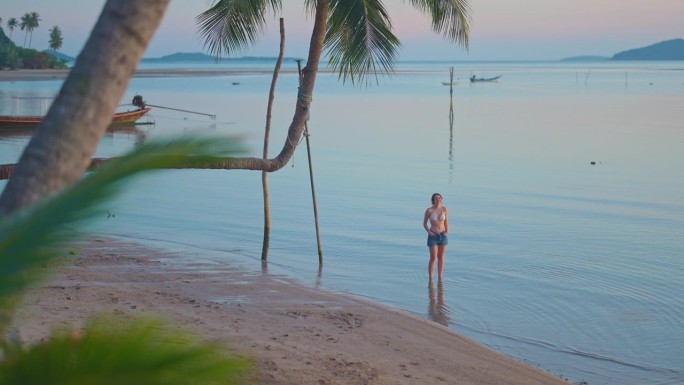 一个女人在沙滩上的椰子树下散步