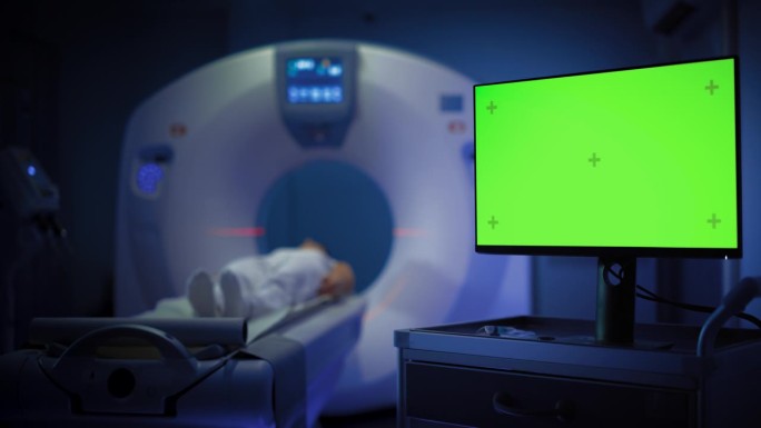 一名女性患者在CT或MRI高科技设备上接受脑部扫描的中景。显示显示器显示绿色屏幕模型模板。医学实验室