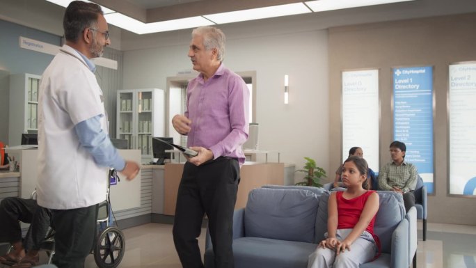 印度老人和他的孙女去医院做健康检查:医生和病人及其父亲谈话的照片，让他们放心化验结果