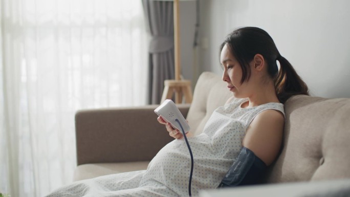 一位年轻的孕妇正在家里量血压