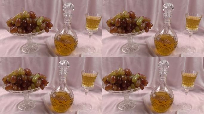 水晶花瓶与葡萄，水晶醒酒器和水晶饮用玻璃与白葡萄葡萄酒是在一个淡粉色缎面背景。