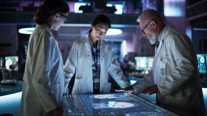 现代医院医学研究中心:不同的同事聚集在交互式触摸屏桌旁，屏幕上显示着大脑的CT扫描。医生讨论中风后的
