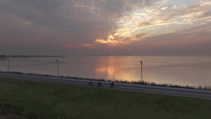 绝美夕阳晚霞下梁子湖湖边绿道骑自行车的人