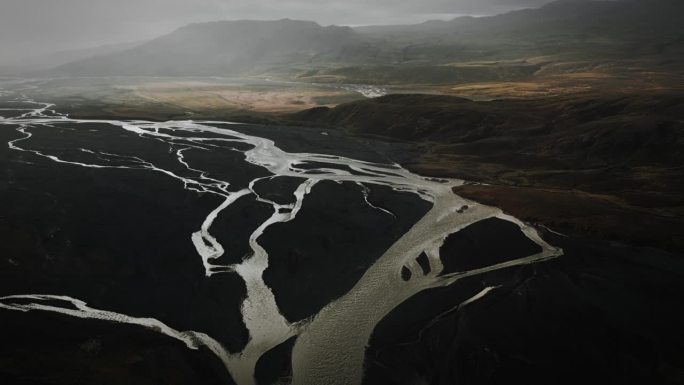 空中倾斜托尔山谷，飞越冰川河流流经黑色火山山脉，thorsmörk冰岛戏剧性的喜怒无常的景观