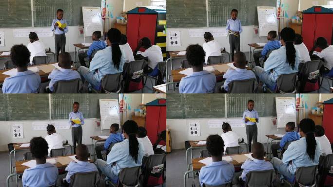 特写镜头。在非洲的一间教室里，一个非洲黑人学生站起来给全班同学读书