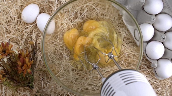 用电动手持式打蛋器准备煎蛋，自动打蛋器俯视图，背景是大麦秸秆和鸡蛋，自制农田概念