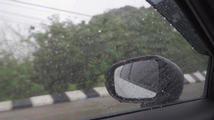 在大雨中开车旅行时天气很恶劣。中午从侧窗往外看，雨下得很大。
