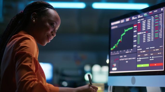 女人，用电脑屏幕和交易图、图表或夜间股市统计数据研究或监控涨幅。非洲分析师或交易员撰写数字加密，数字