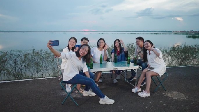 快乐的亚洲朋友在户外用智能手机自拍庆祝圣诞夜和新年，新年假期和假期。年轻人一起庆祝，享受。