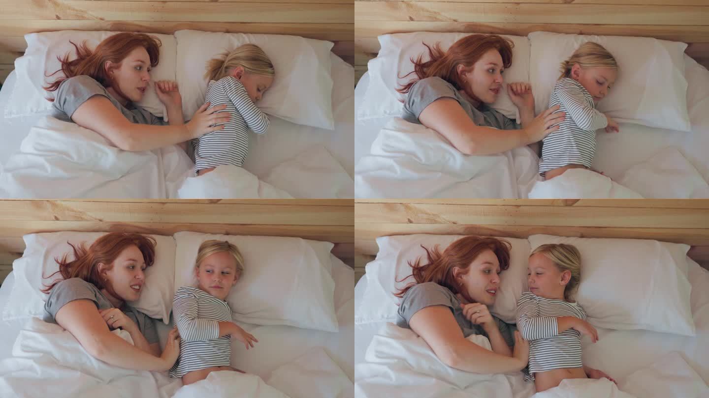 床上，母亲醒来后抚摸着女儿，在家里一起熟睡。微笑，放松，或者和一个女人和一个女孩一起躺在卧室里度过周