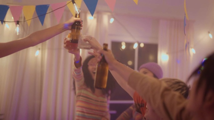 一个可爱的女孩在家里的聚会上和朋友们一起唱歌，喝啤酒，碰杯。