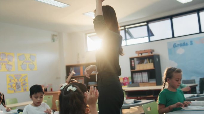 在教室里，一群快乐的小学生举起手臂回答一位漂亮的女老师的问题。