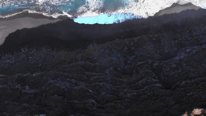在特内里费岛高高的悬崖上，绿色的棕榈树俯身向下，露出蓝色的海浪拍打着海岸