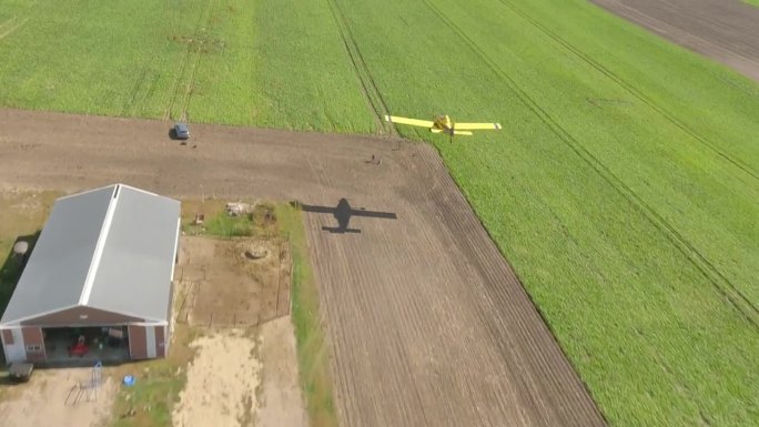 小型螺旋桨作物喷粉机飞机在农村机场起飞区的草地上低空飞行的FPV无人机镜头