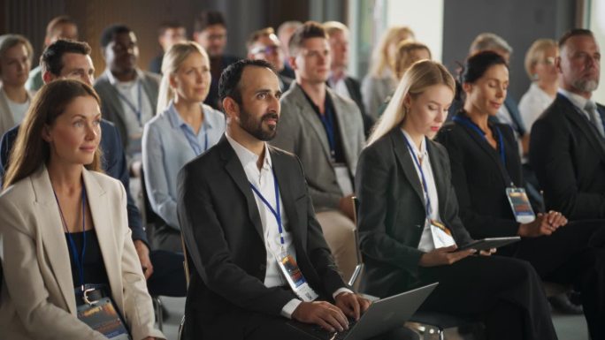 在国际医学峰会上，形形色色的生物制药企业家坐在人群中，用笔记本电脑、平板电脑做笔记。男女业界领袖聆听
